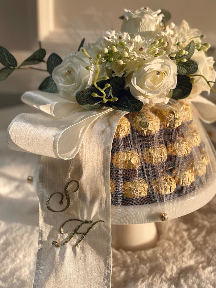 Luxurious Ferrero Rocher tower adorned with white roses and ribbon.