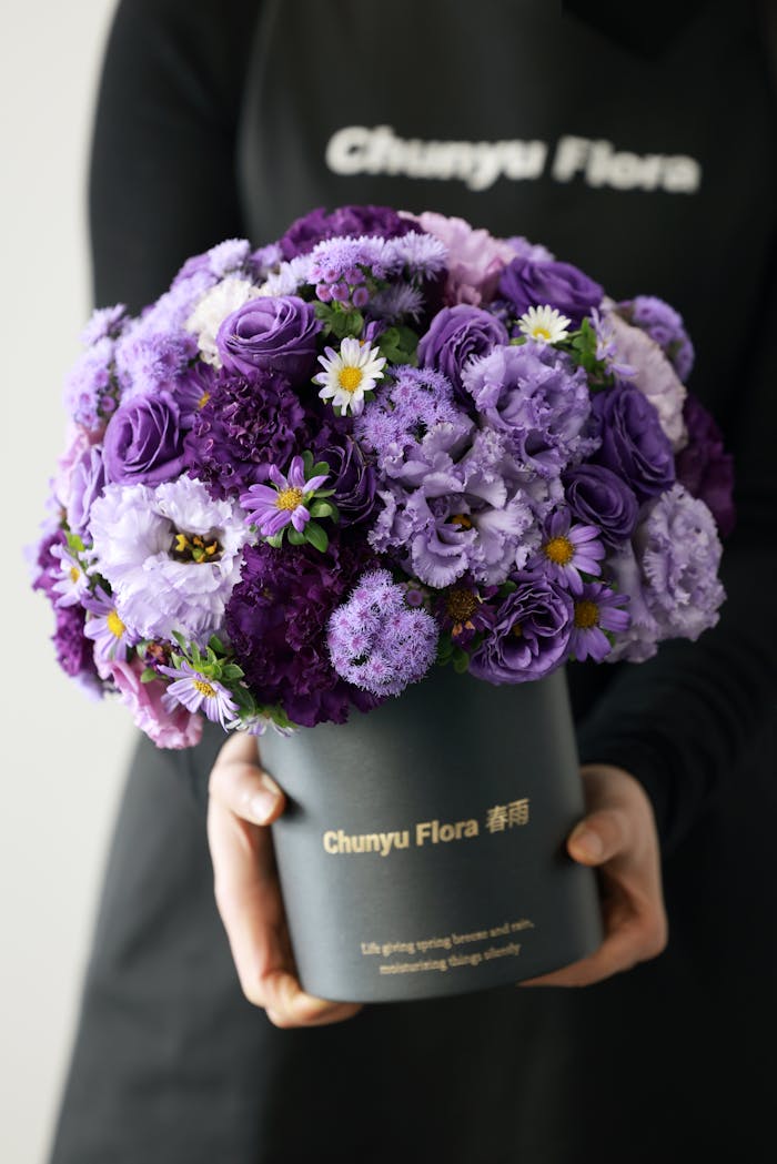 A vibrant purple floral arrangement featuring diverse blossoms in a sleek black vase, perfect for special occasions.