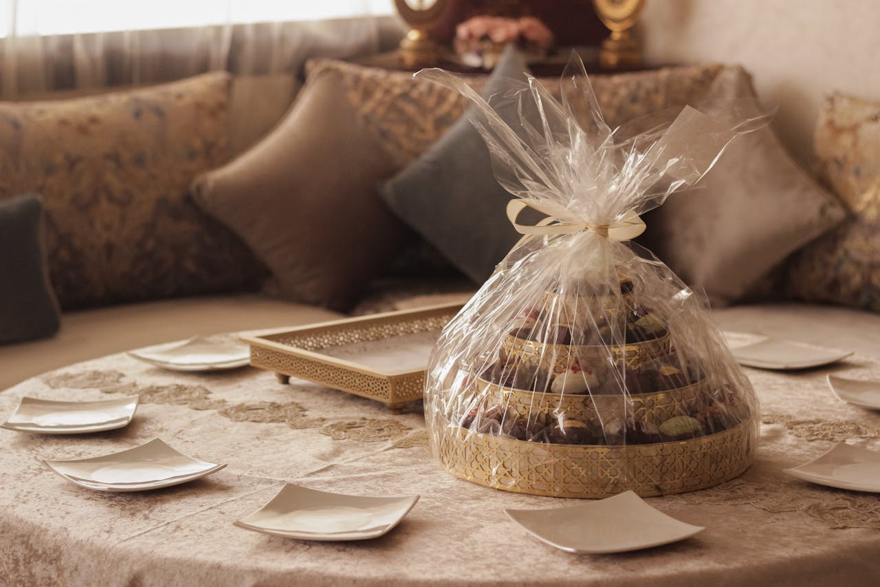 A beautifully wrapped gift tray of assorted sweets on an ornate table setting, perfect for celebrations.